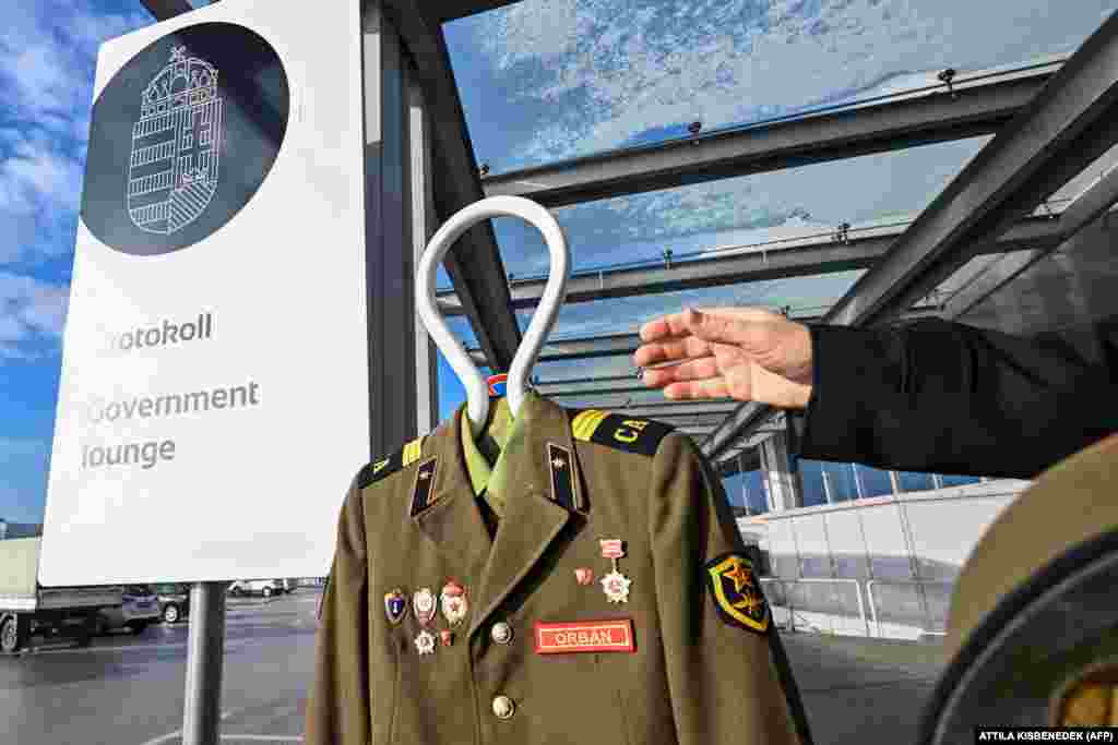 Активист венгерской общественной организации Ujratervezes (&laquo;Переработка&raquo;) держит руку рядом с российской униформой с надписью "Орбан" перед протокольным входом в зал ожидания венгерского правительства в аэропорту Будапешта.