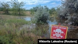 Предупреждающий знак вблизи области затопления после подрыва плотины Каховской ГЭС, окрестности город Снигиревка Николаевской области Украины, 11 июня 2023 года