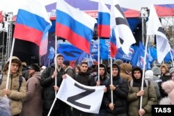 Люди с российскими флагами на площади Ленина в Астрахани во время концерта, посвященного участникам «специальной военной операции» (так Москва называет вторжение России в Украину). 22 февраля 2023 года