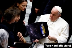 Папа Римський Франциск із календарем «Азовсталь», якого він отримав від Юлії Федосюк, дружини бійця полку «Азов» Арсенія Федосюка, під час щотижневої загальної аудієнції у Ватикані, 21 грудня 2022 року