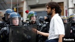 Un protestatar le întinde un trandafir jandarmilor în timpul unei manifestații la Paris, în timpul unei zile de greve și proteste la nivel național pentru salarii mai mari, 18 octombrie