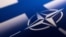 Лягатып NATO на фоне сьцягу Фінляндыі 