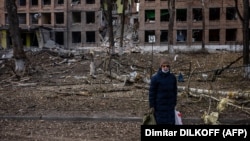 Жінка на тлі зруйнованої російськими обстрілами будівлі у Василькові Київської області, 27 лютого 2022 року