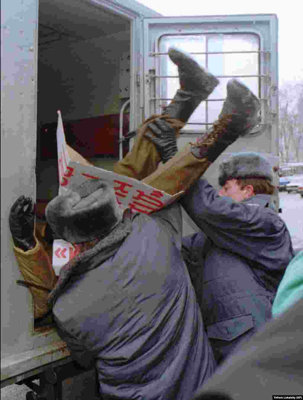 Міліція затримує учасника акції протесту в Києві 12 січня 1996 року. Кілька членів українського парламенту організували протест проти договору про без'ядерний статус України. У той час, коли міліціонери запихають його в міліцейський фургон, він тримає плакат із вимогою відставки тодішнього міністра оборони України Валерія Шмарова