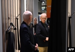 Алесь Беляцкий в сопровождении жены Натальи Пинчук примеряет новый костюм в торговом центре в Вильнюсе, 14 декабря 2025 года, на следующий день после освобождения из тюрьмы. Фото AFP