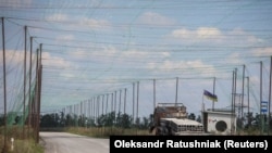 Згорілий автомобіль і антидронні сітки, встановлені над дорогою поблизу Добропілля, Донецька область, 10 серпня 2025 року