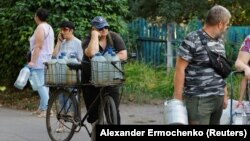 Місцеві жителі стоять у черзі за водою до автоцистерни в окупованому Донецьку, 29 липня 2025 року