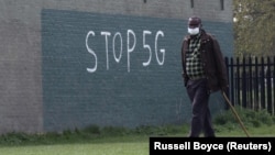 Чоловік у масці на обличчі під час спалаху коронавірусної хвороби (COVID-19) проходить повз графіті з написом «STOP 5G» в Лондоні, Великобританія, 8 квітня 2020 року. 