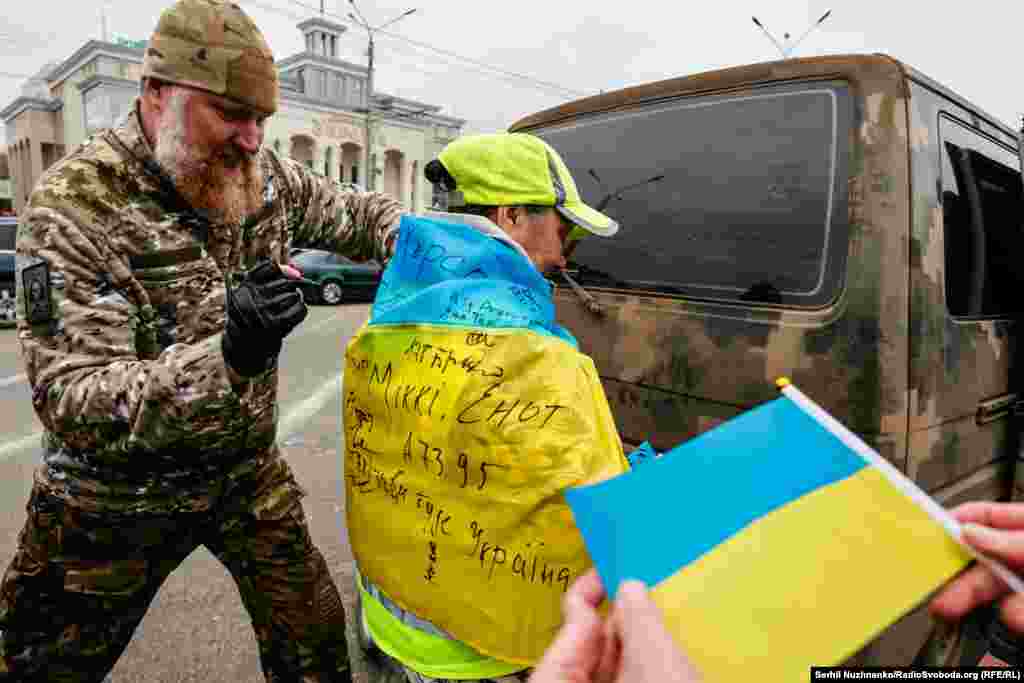 День звільнення Херсону від російської окупації, що тривала з березня по листопад 2022 року. Військовий ЗСУ підписує прапори херсонців, що вийшли зустрічати українських бійців