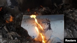 Zapaljena fotografija libijskog predsednika Moamera Gadafija, Bengazi, 28. februar 2011.