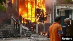 Men walk past a burning building during the 2010 violence in the Kyrgyz city of Osh that left hundreds dead. 