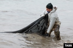 Співробітник МНС РФ збирає плями нафти на поверхні в селі Вольна під час операції з ліквідації розливу нафти після аварії танкерів «Волгонєфть 212» і «239» у Керченській протоці