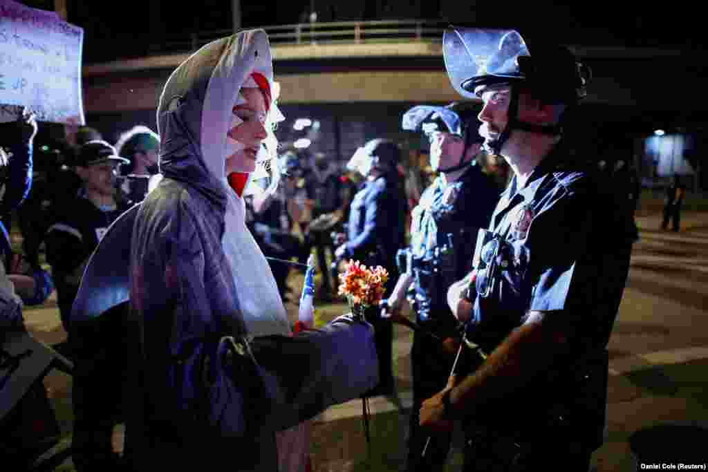 Учасниця протесту у костюмі акули простягає поліцейському квіти під час акції протесту «Ні королям» проти політики президента США Дональда Трампа. Лос-Анджелес, Каліфорнія, США, 18 жовтня 2025 року