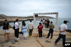 Люди фотографируются на фоне Тайваньского пролива в туристическом месте под названием "68 морских миль" на острове Пинтань, самой близкой к главному острову Тайваня точке Китая, в провинции Фуцзянь на юго-востоке Китая, 24 мая 2024 года