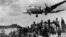 Un avion american de tic C-54 Skymaster în curs de aterizare la Baza militară aeriană Tempelhof de la Berlin, în timp ce berlinezii privesc cu speranță la 10 august 1948. Podul aerian a funcționat timp de 15 luni după ce sovieticii au blocat orașul. Circa 101 dintre participanții la operațiune au murit, între care 40 de britanici și 31 de americani, în cea mai mare parte a lor datorită unor accidente nelegate de zbor.