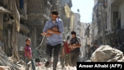 Чоловіки виносять дітей із зруйнованого російським обстрілами кварталу Алеппо. Сирія, 11 вересня 2016 року
