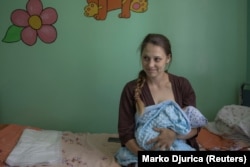 24-летняя Ирина Будакова держит на руках своего сына, родившегося двумя днями ранее. Родильный дом в Покровске, 6 июля 2022 года