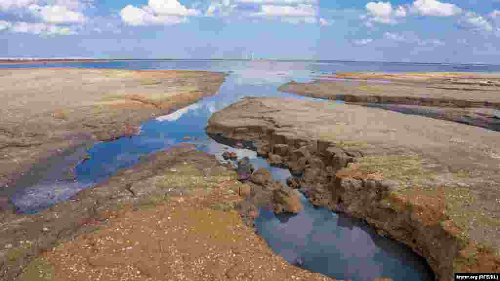 Вода сохранилась лишь в восточной части озера. На переднем плане &ndash; птичьи &laquo;ванны&raquo;. Вдалеке виднеются ветрогенераторы функционирующей Восточно-Крымской ветряной электростанции