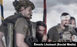 Як і на оригінальній картині Іллі Рєпіна «Запорожці пишуть листа...», так і на фотопостановці Емеріка Луіссе присутні замотані прапори – синьо-жовтий і червоно-чорний