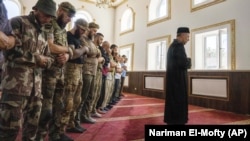 "Umma" Ukrayina musulmanları diniy idaresiniñ sabıq müftisi Said İsmagilov (sağ tarafta) Qurban bayramınıñ birinci künü namaz vaqtında Rusiye ile cenkte Ukrayina içün cenkleşken musulman askerlernen beraber. Donetsk vilâyetiniñ Konstantinovka camisi, 2022 senesi oraq ayınıñ 9-ı