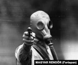 Un bărbat neidentificat la un exercițiu de tragere cu pistolul purtînd mască de gaze în 1967.
