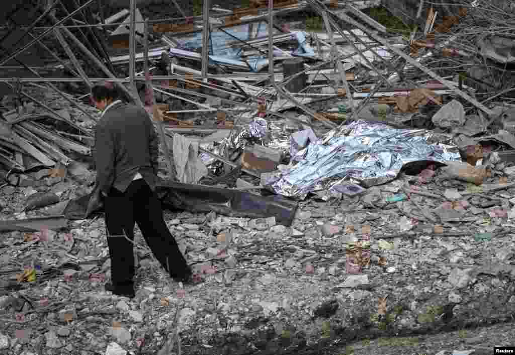 Чоловік проходить повз накриті тіла жертв російської повітряної атаки, які лежать біля їхнього зруйнованого будинку у селі Лапаївка на околиці Львова, 5 жовтня 2025 року