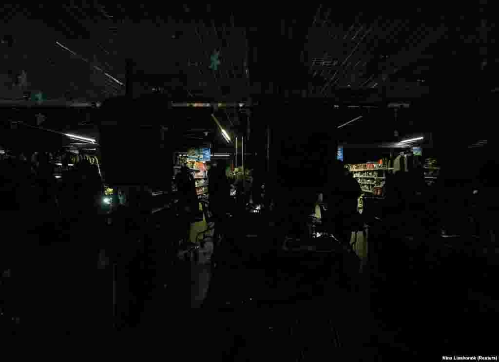 Люди в супермаркете в Одессе, который продолжает обслуживать покупателей благодаря дизельным генераторам, 13 декабря 2025 года.