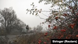 Поліцейський цілиться з гвинтівки під час загрози удару російського FPV, на шляху до евакуації цивільних із прифронтового міста Гуляйполе. Запорізька область, Україна, 14 листопада 2025 року