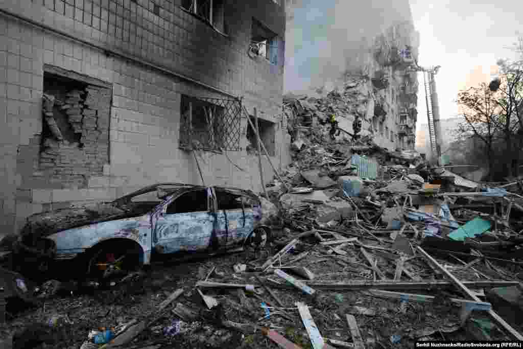 Сгоревший автомобиль у дома в Киеве, попавшего под ракетный удар