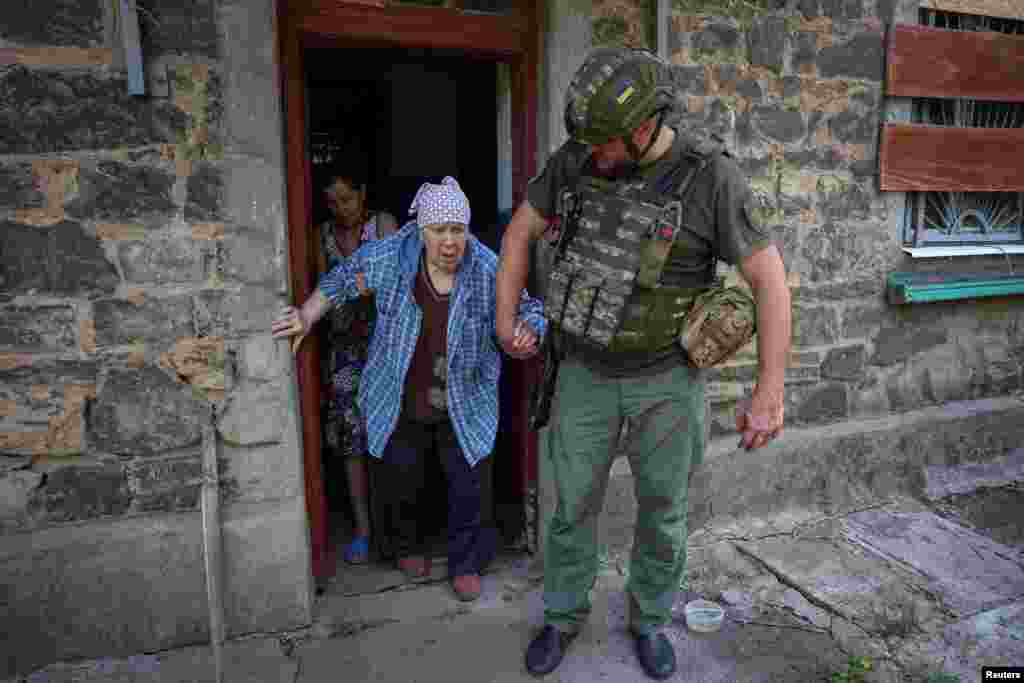 یک افسر پلیس زنی را از خانه‌اش در شهر کستیانتینیوکا، در منطقهٔ دونتسک اوکراین، تخلیه می‌کند