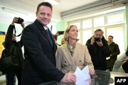 Candidatul prezidențial și primarul Varșoviei, Rafal Trzaskowski, în timp ce votează alături de soția sa, la o secție de votare din Varșovia pe 18 mai.