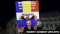 Плакат на акции протеста, на котором изображен руководитель России Владимир Путин и Кэлин Джорджеску, прошедший во второй тур на выборах президента Румынии. Конституционный суд отменил эти результаты в связи с возможным иностранным вмешательством. Бухарест, ноябрь 2024 года