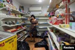 Женщина собирает товар в продуктовом магазине перед его закрытием из-за наступления российских войск. Покровск, 23 августа 2024 года