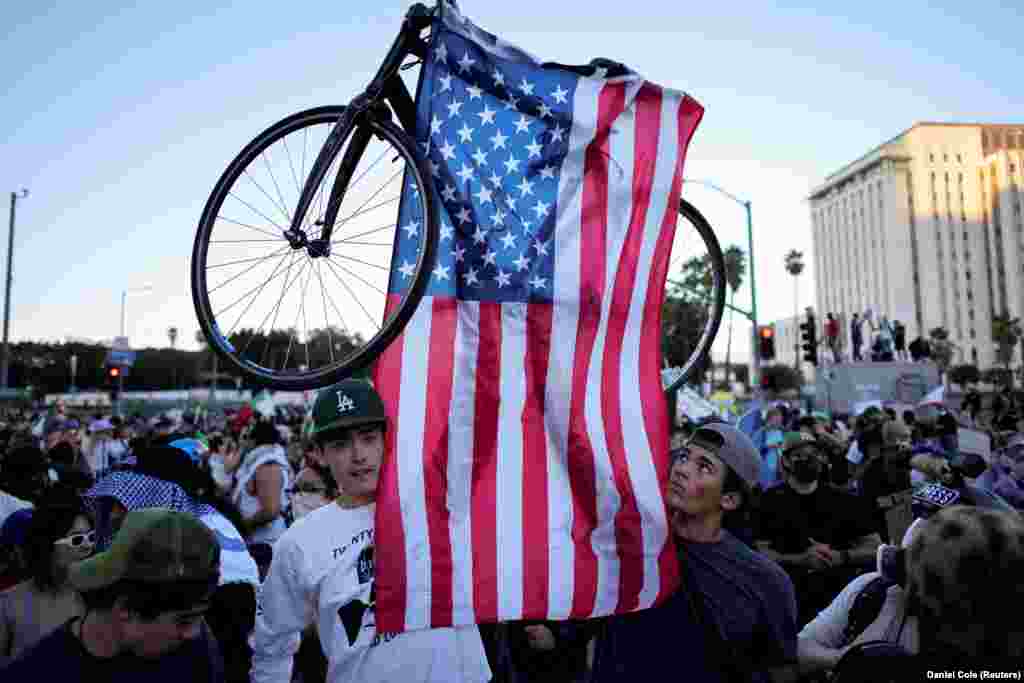 Демонстранти тримають велосипед з американським прапором під час акції протесту «Ні королям» проти політики президента США Дональда Трампа біля мерії в Лос-Анджелесі, Каліфорнія, США, 18 жовтня 2025 року