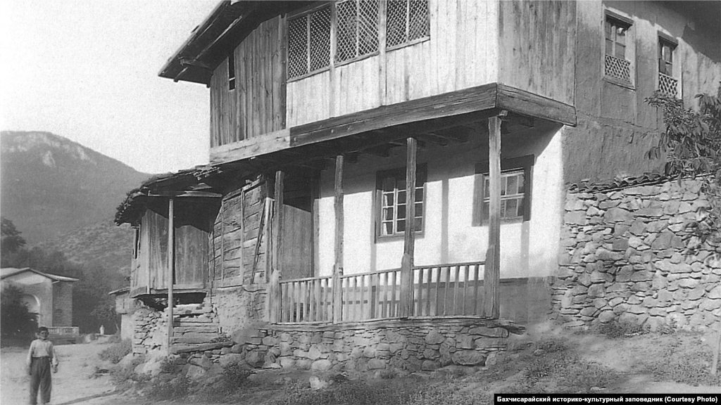 Сільський будинок. Південно-Західний Крим, 1920-ті. &nbsp; Стандартний інтер'єр головної кімнати включав відкритий камін з димарем і підвішений до нього на ланцюгу казан. Уздовж стін стояли низькі диванчики з матрацами і подушками, поруч &ndash; столики. Для прикраси стін використовувалися численні рушники, а для підлоги &ndash; килими