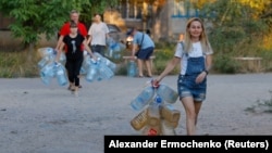 Місцеві жителі йдуть за водою до автоцистерни в окупованому Донецьку, 21 серпня 2025 року