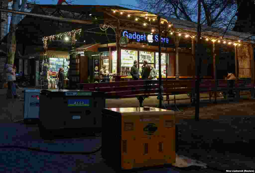 Люди на уличном рыноке, который также берет энергию от генераторов, во время отключения света после недавних российских атак, 15 декабря 2025 года.