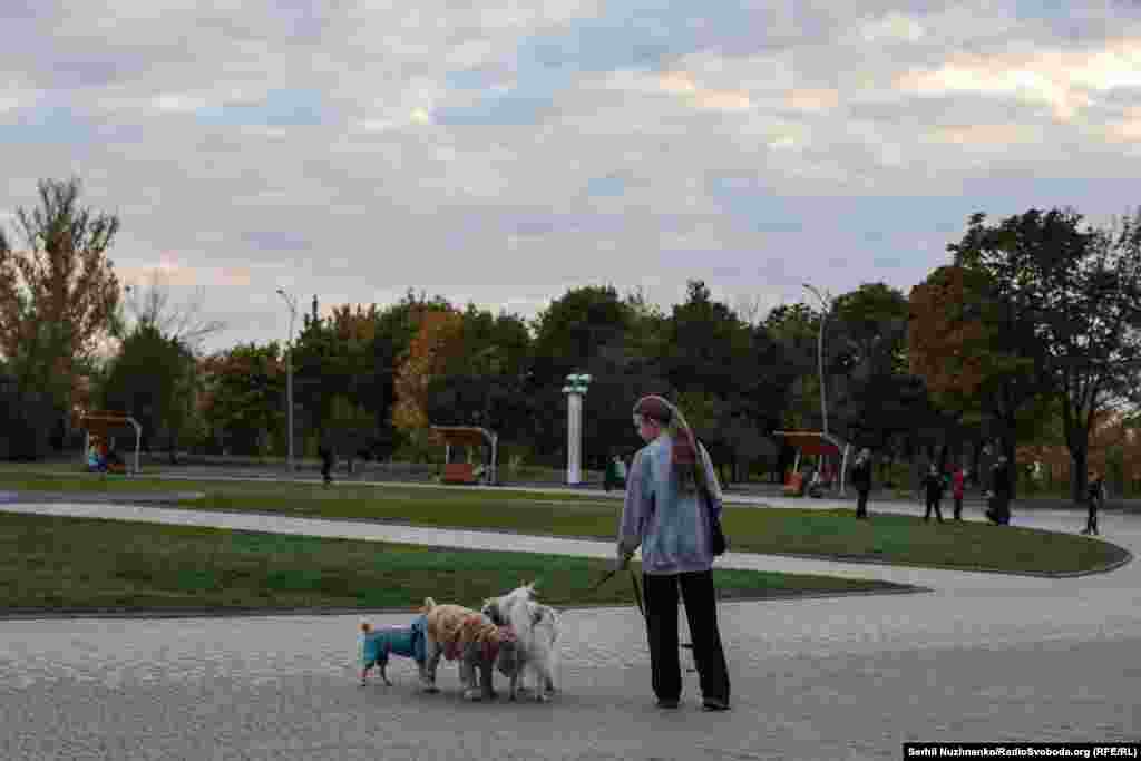 Дівчина гуляє з собакою в парку Ювілейний, де є флагшток із прапором України, який російські війська останнім часом намагаються знищити FPV-дронами