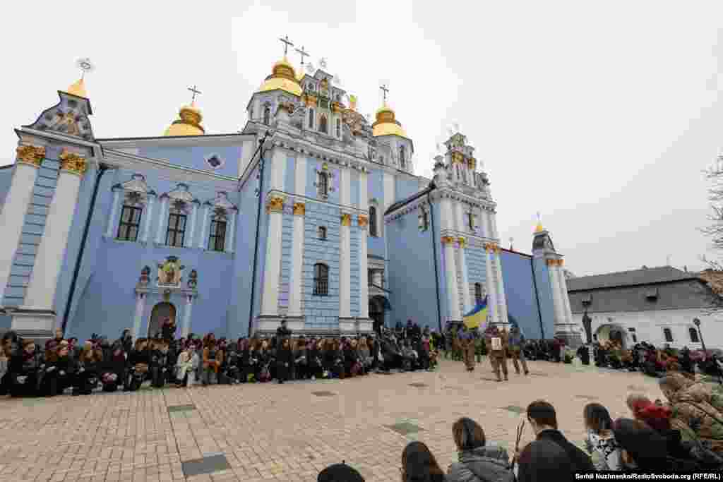 Люди стоять на колінах, коли труну з тілом загиблого Костянтина Гузенка виносять з Михайлівського собору в Києві, 7 листопада 2025 року