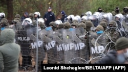 Polşanyň howpsuzlyk işgärleri we Belarusyň serhet araçäklerindäki migrantlar.