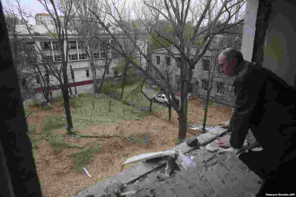 Чоловік дивиться з вікна пошкодженого уламками російського КАБу гуртожитку в Запоріжжі, 11 листопада 2024 року. Приліт припав на подвір'я житлової забудови. Пошкоджені будинки навколо та гуртожиток, в якому проживають, зокрема, й ВПО