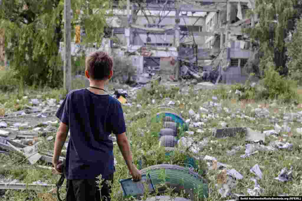 Хлопчик дивиться на те, що залишилося від його школи, яку зруйнував авіаудар російської армії. Уся трава навколо всипана розкиданими вибухом зошитами і книжками. Бахмут, Донецька область, червень 2022 року.За час російської збройної агресії в Україні повністю знищені більше ніж 400 шкіл, а кожна сьома школа зазнала пошкоджень
