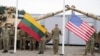 Салдаты трымаюць літоўскі і амэрыканскі сьцягі падчас цырымоніі адкрыцьця амэрыканскага вайсковага лягеру Herkus у Падбродзьдзі, Літва, 30 жніўня 2021 году