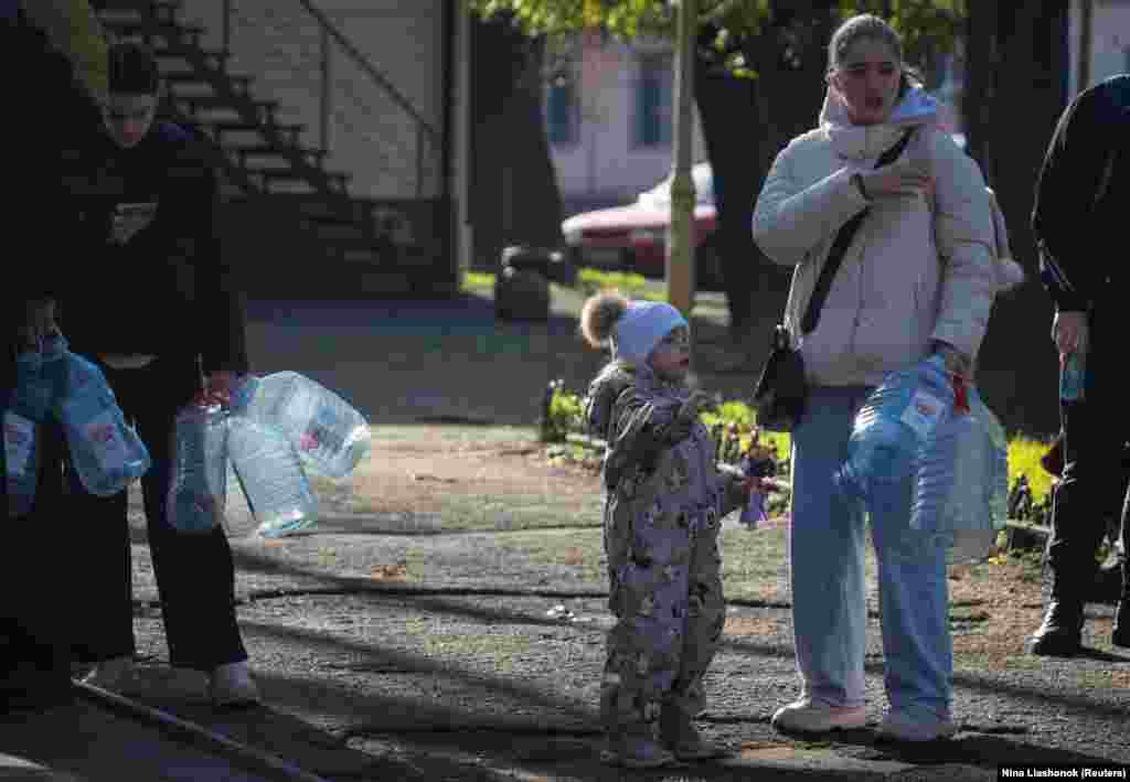 Жители Одессы – взрослые и дети – стоят в очереди, чтобы наполнить бутылки питьевой водой после того, как в результате российской атаки была повреждена критически важная гражданская инфраструктура города, 13 декабря 2025 года.